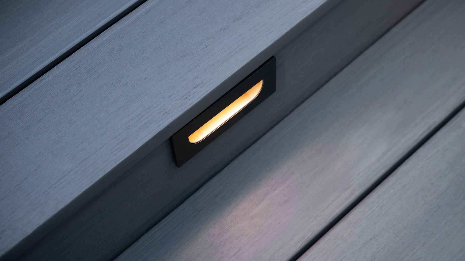 Grey Timbertech decking displaying optional stair lighting. This image is promoting custom deck design by Deck Teck