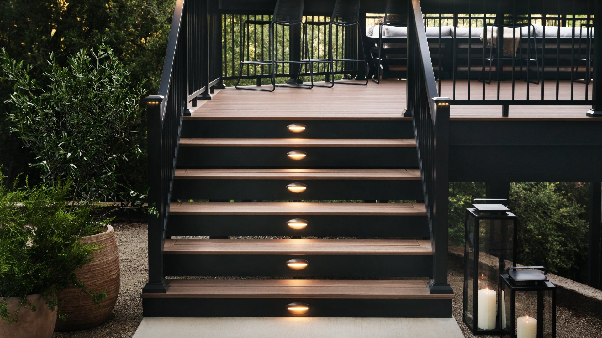 Deck staircase in Mahogany color Timbertech decking and black railing displaying optional stair lighting. This image is promoting custom deck design by Deck Teck