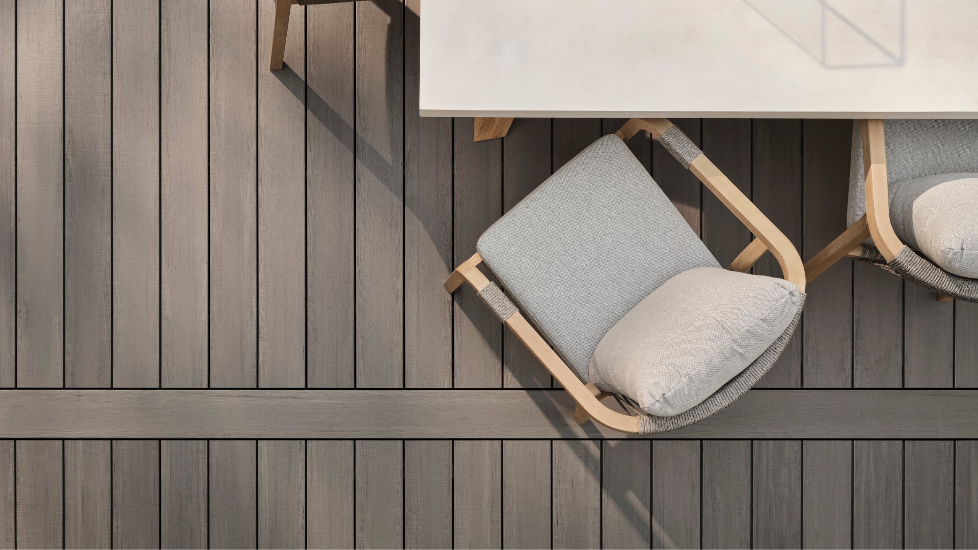 Overhead view of grey Timbertech decking and luxury deck furniture in dappled sunlight. This image is promoting custom deck design by Deck Teck